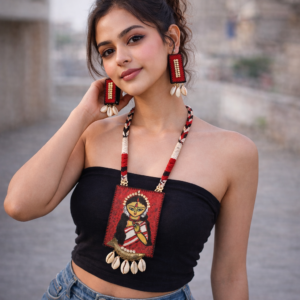 Young Indian woman wearing boho cowrie shell earrings and embroidered goddess Kali necklace with black strapless top and denim jeans.